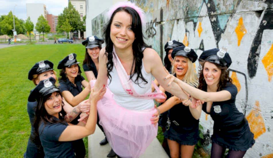 Junggesellinnen in US Polizeiuniformen halten die Braut beim Outdoor JGA-Fotoshooting fest